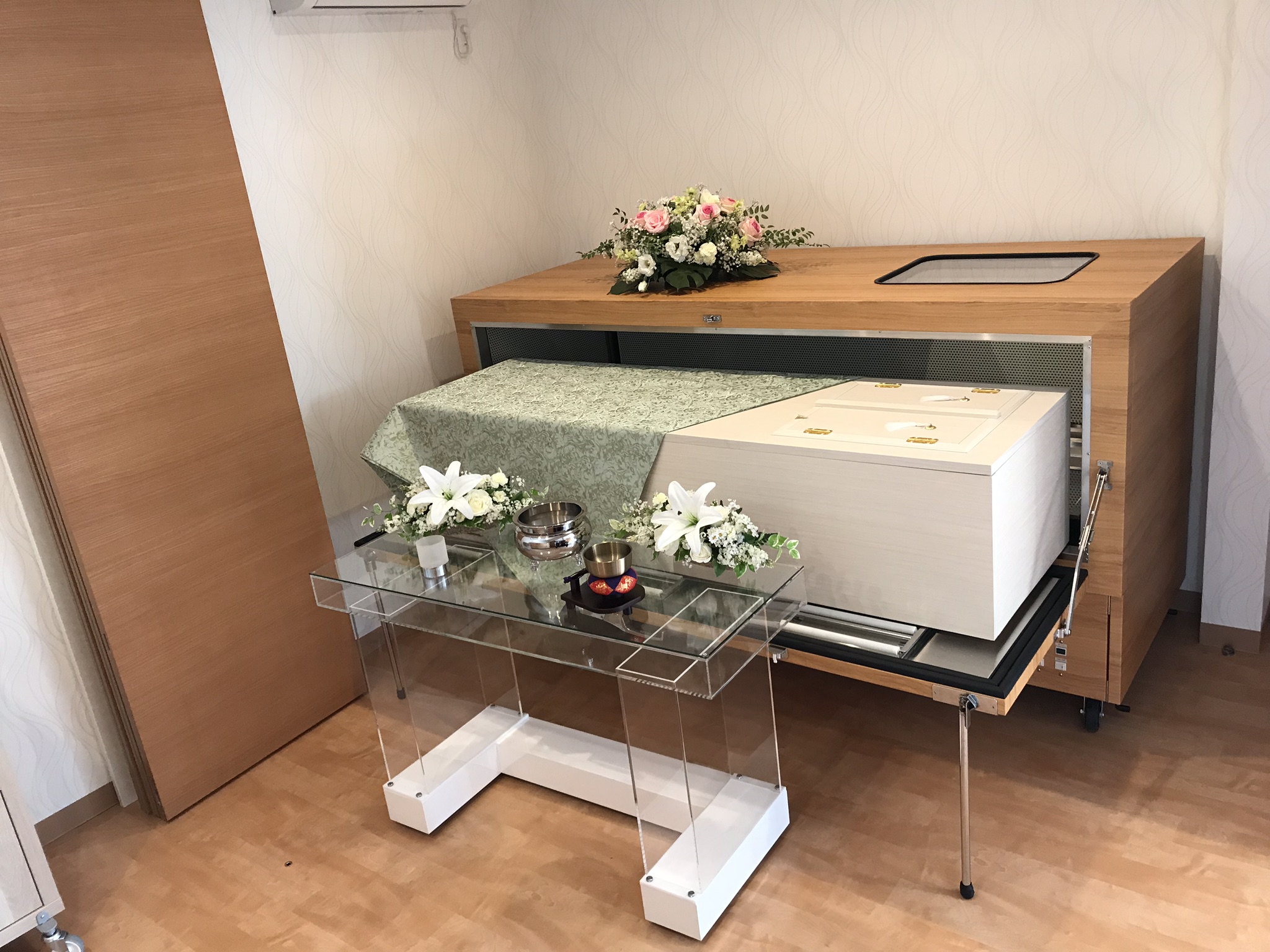 熊谷市小さい葬儀受付センターの安置室に置かれた白い直葬用棺と供花テーブル、熊谷市 直葬